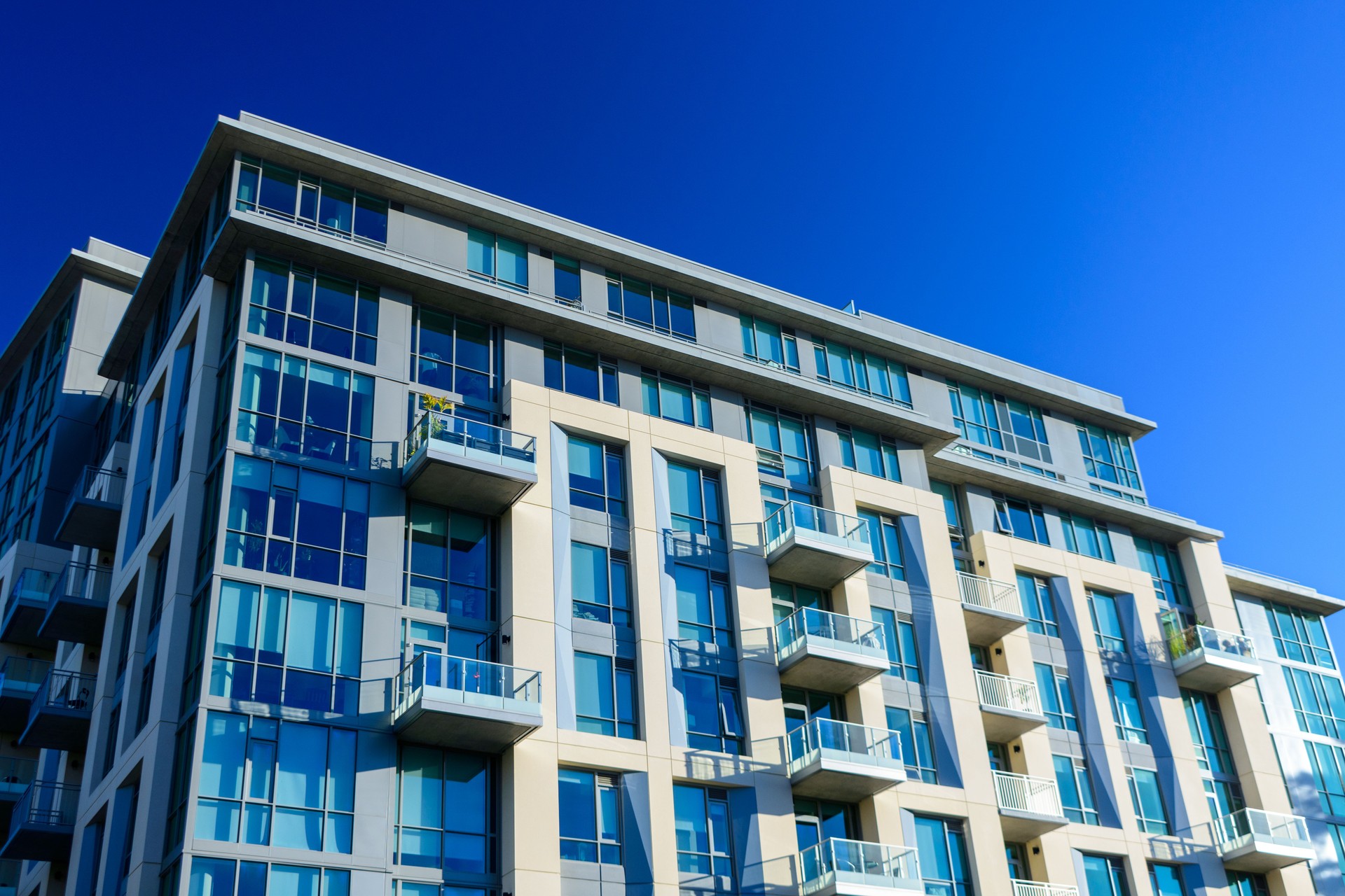 Exterior low-angle view of a modern high-rise apartment building with large glass windows and balconies